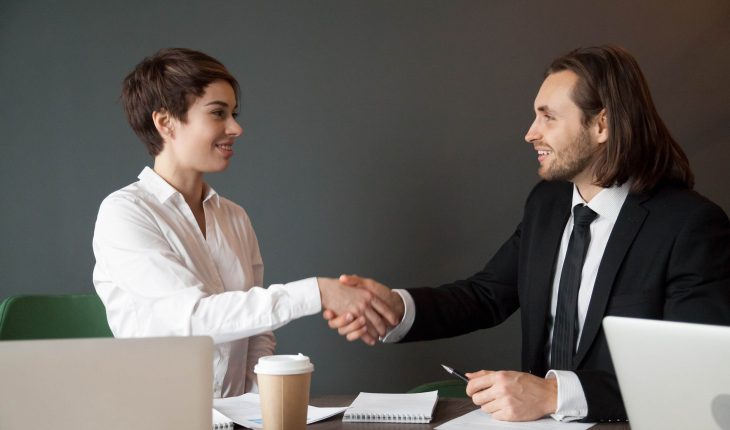 Business partners shaking hands after closing successful corporate deal at company meeting, businesspeople greeting with handshake during negotiations in boardroom. Concept of partnership, cooperation